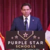 Florida governor Ron DeSantis standing at a podium with a sign that reads Purple star schools