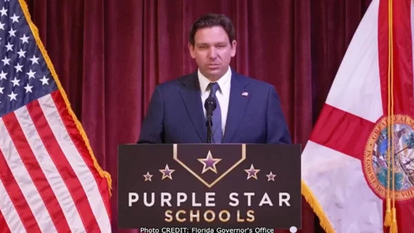 Florida governor Ron DeSantis standing at a podium with a sign that reads Purple star schools